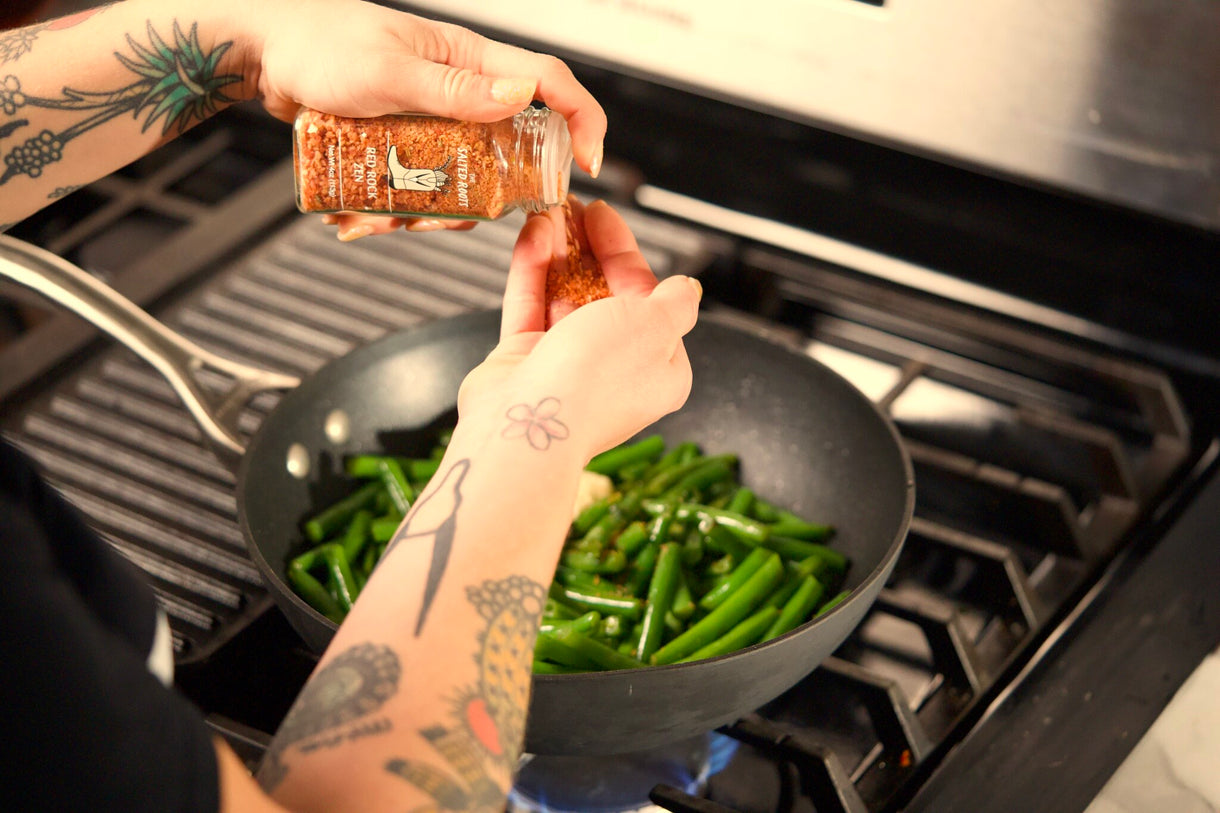 Sprinkling The Salted Roots Red Rock Zen over green beans blistering in a hot pan